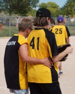 Softball teammates hugging on the field.