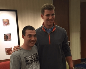 Jon Manning posing and smiling with Eli Manning.