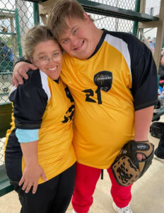 A young male Special Olympic athlete hugging his coach.