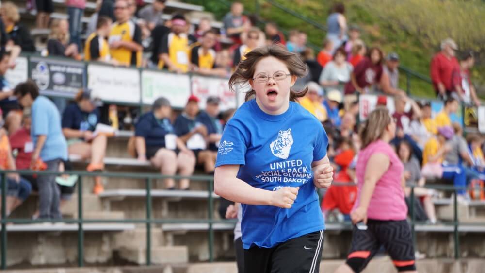 A female Special Olympics athlete running a race.