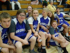Special Olympics basketball teammates smiling and sitting on the court together.
