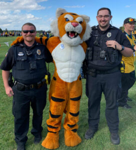 Two policeman standing with a team mascot dressed as a tiger.